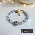Bracelet with blue beads and gold accents on a white surface, featuring 'Sseau Beautiful by Heather' branding.
