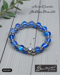 Blue beaded bracelet with silver accents on a wooden surface, featuring the brand 'Sseau Beautiful by Heather'.