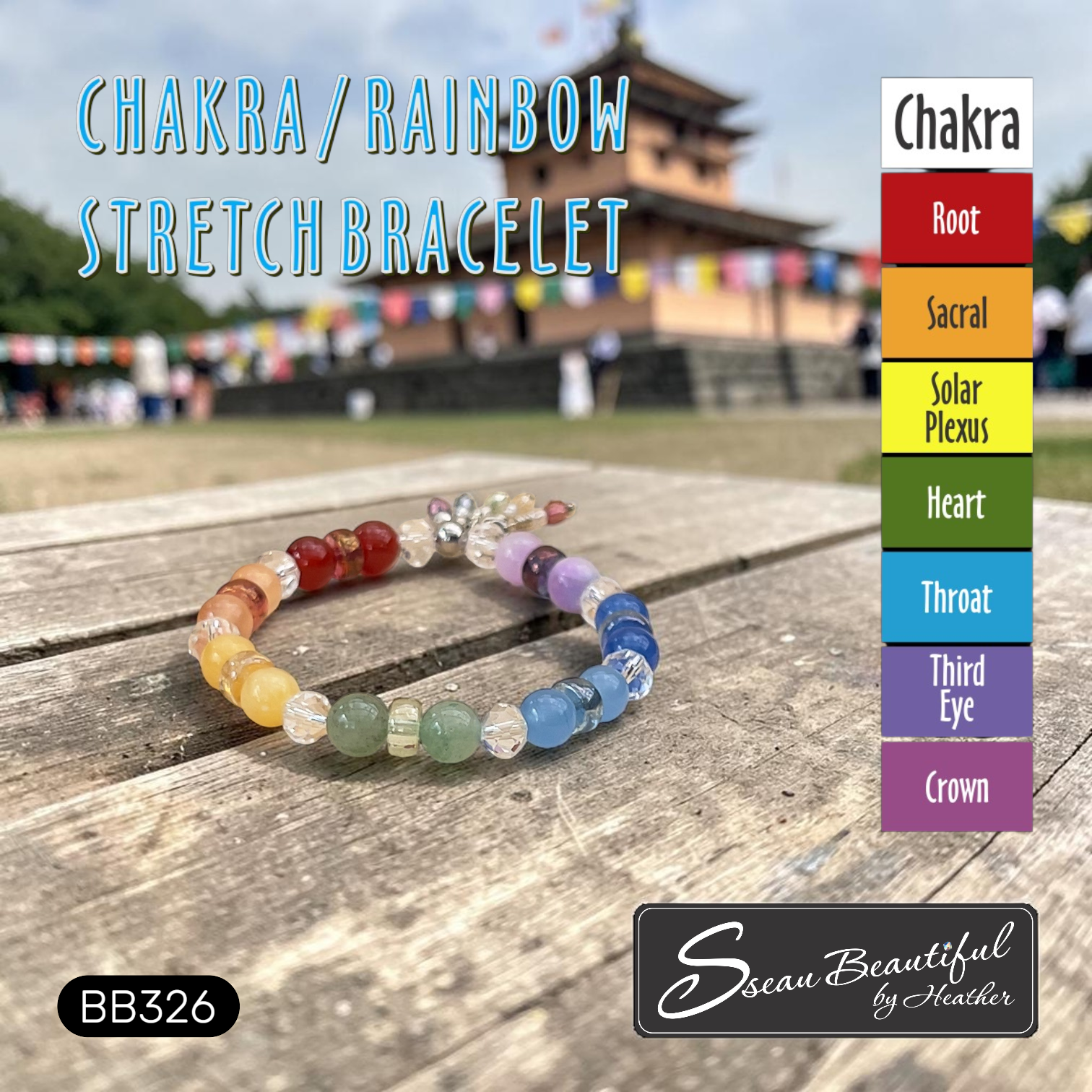Handmade chakra and rainbow stretch gemstone bead bracelet displayed on a rustic wooden table with a blurred temple background, featuring a color alignment guide chart from Root to Crown chakras. Style BB326 by Sseau Beautiful by Heather.