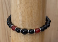 Beaded bracelet with black, red, and silver beads on a wooden post