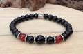 Black beaded bracelet with red accents on a wooden surface