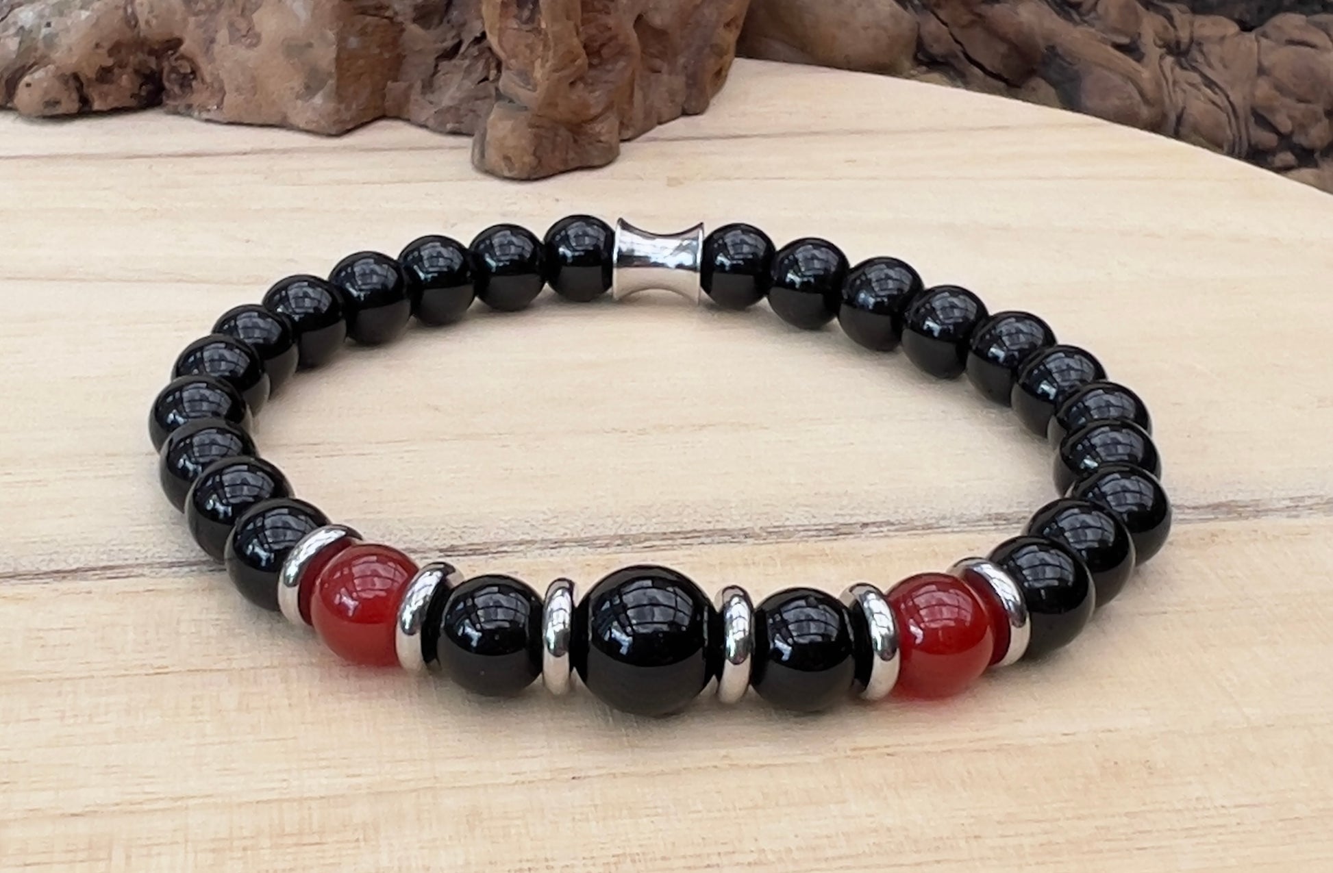 Black beaded bracelet with red accents on a wooden surface