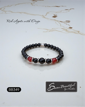 Beaded bracelet with red and black stones on a marble surface, featuring 'Sseau Beautiful by Heather' branding.
