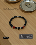 Black beaded bracelet with red accents on a wooden surface, featuring the brand 'Sseau Beautiful by Heather'.