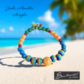 Colorful beaded bracelet on a sandy beach with ocean view