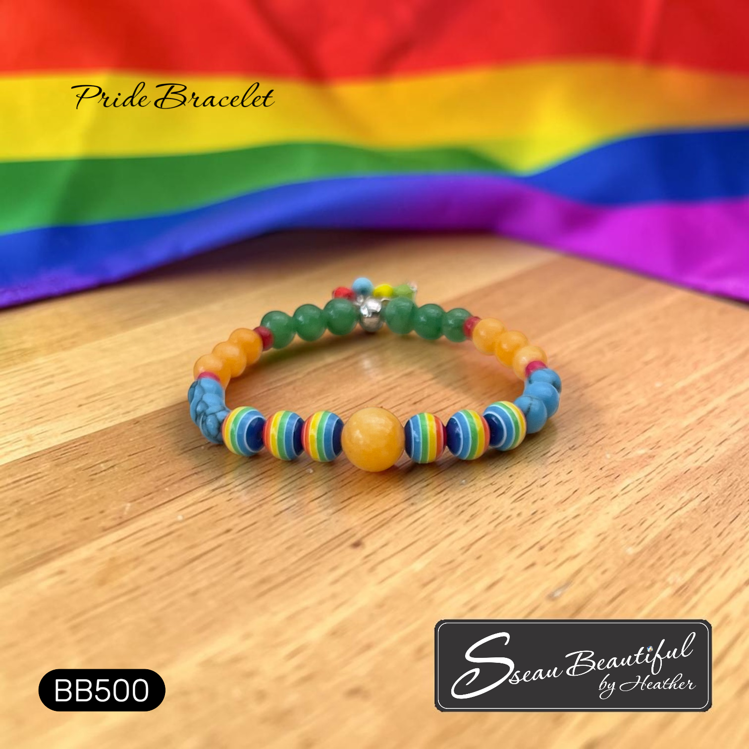 Colorful beaded bracelet on a wooden surface with a LGBTQ2+ rainbow flag in the background