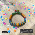 Colorful beaded bracelet on a confetti covered wooden surface with 
