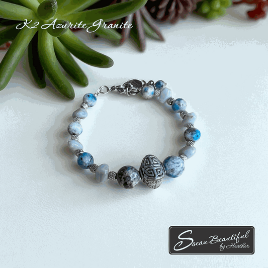 Women's blue and grey adjustable bracelet on a white surface with succulents in the background