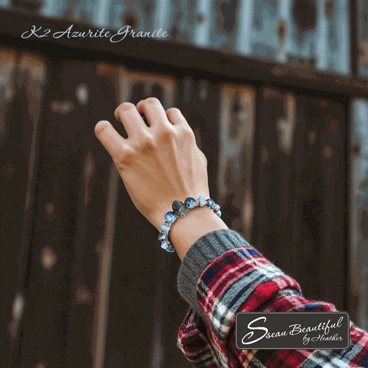 Women's blue and grey adjustable bracelet on a woman's wrist with a wooden fence in the background