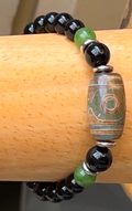 Beaded bracelet with black, green, and patterned beads on a wooden surface