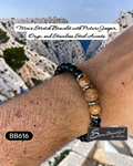 Men's stretch bracelet with picture jasper, onyx, and stainless steel accents on a wrist with a mountainous background.