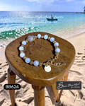 Adjustable bracelet with blue beads and gold accents on a wooden stool by the beach.