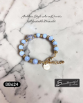 Bracelet with blue beads and gold accents on a marble surface, featuring 'Sseau Beautiful by Heather' branding.