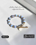 Bracelet with blue beads and gold accents on a white surface, featuring 'Sseau Beautiful by Heather' branding.
