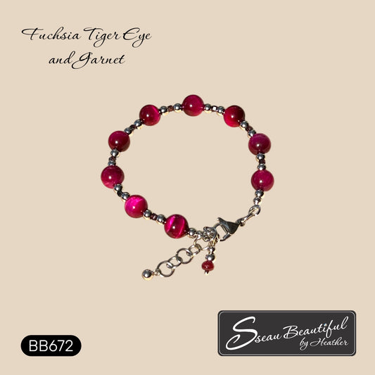 A beaded bracelet featuring fuchsia tiger's eye and garnet beads with silver stainless steel spacer beads and a silver clasp, displayed on a beige background with brand text 'Sseau Beautiful by Heather' and model number 'BB672'.