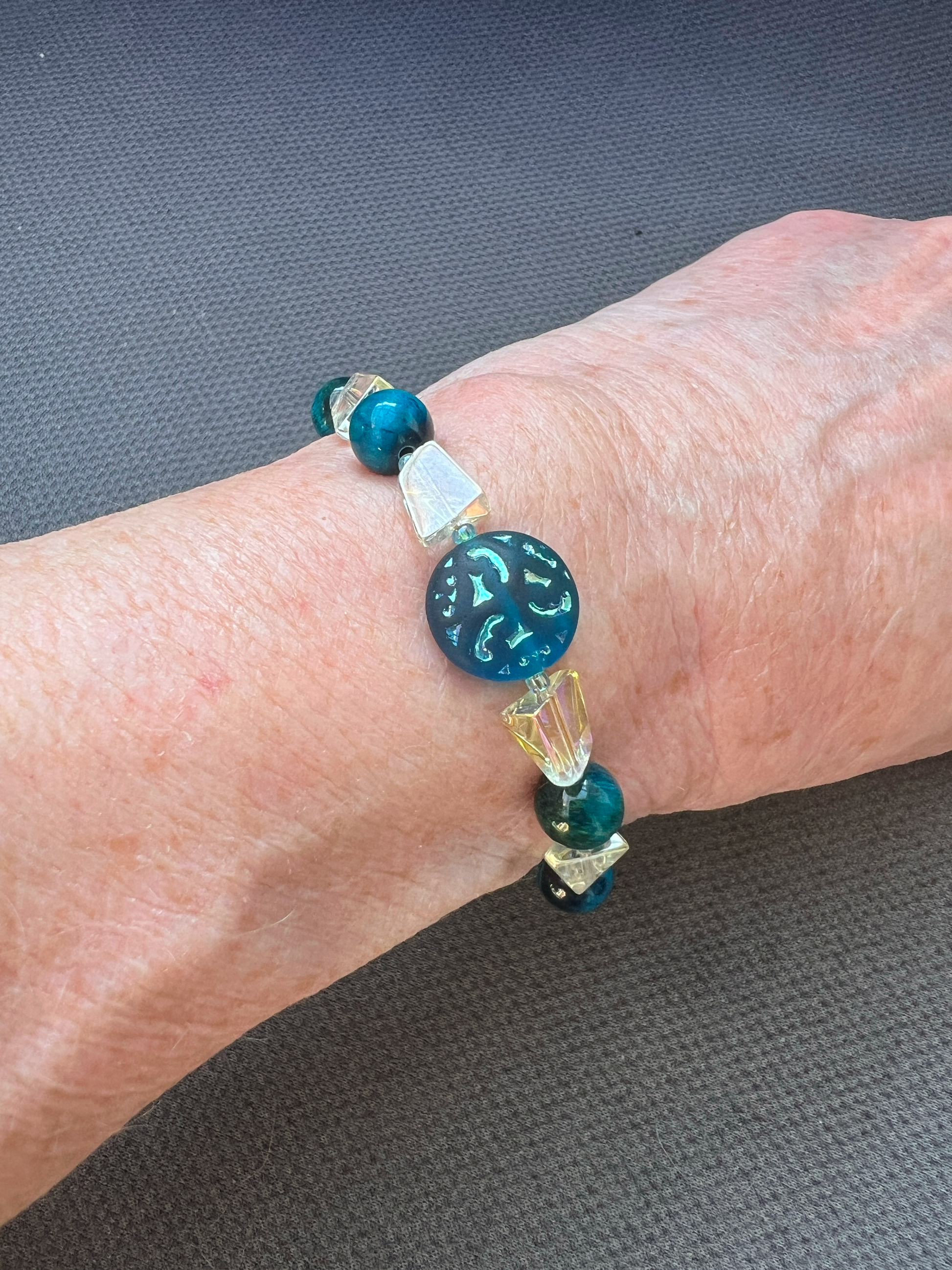 Video shows a woman wearing an Adjustable 6.69 inch bracelet with a Czech Glass focal, Blue Tiger Eye rounds, AB finished Glass Nuggets, matching dangle, and a Stainless Steel Lobster Clasp and Extender 
