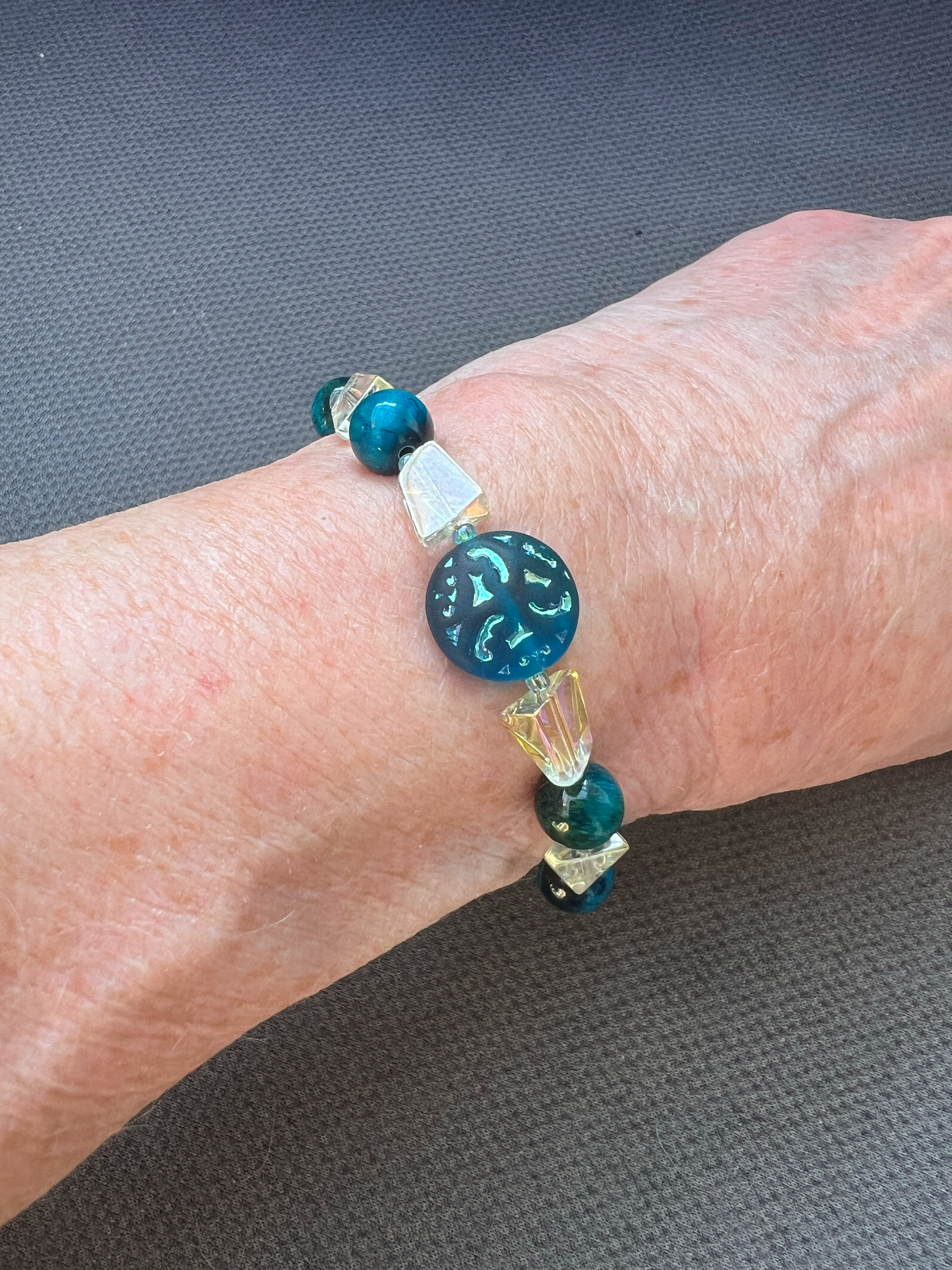 Video shows a woman wearing an Adjustable 6.69 inch bracelet with a Czech Glass focal, Blue Tiger Eye rounds, AB finished Glass Nuggets, matching dangle, and a Stainless Steel Lobster Clasp and Extender 