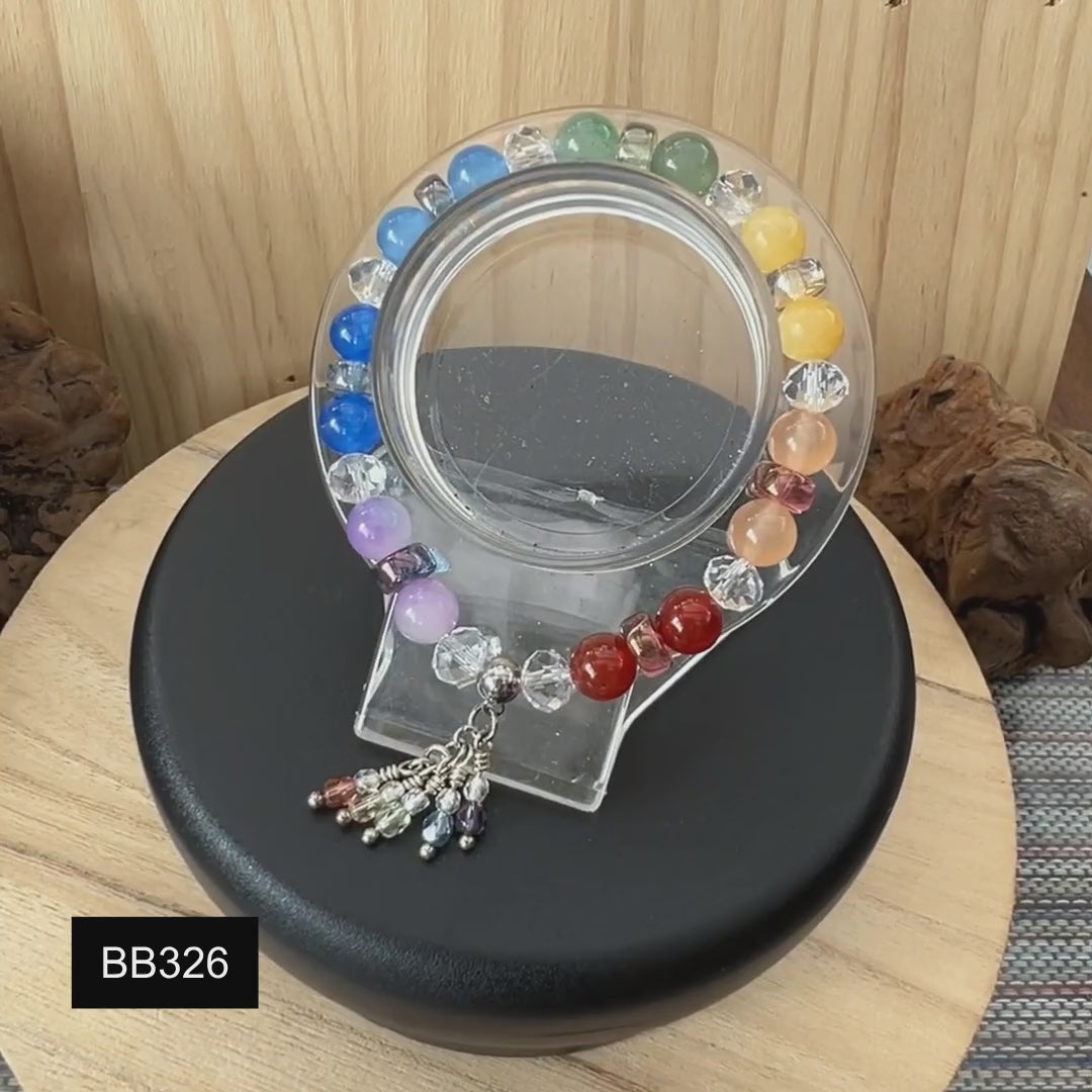 Multi-coloured stone and crystal stretch bracelet on a revolving stand.